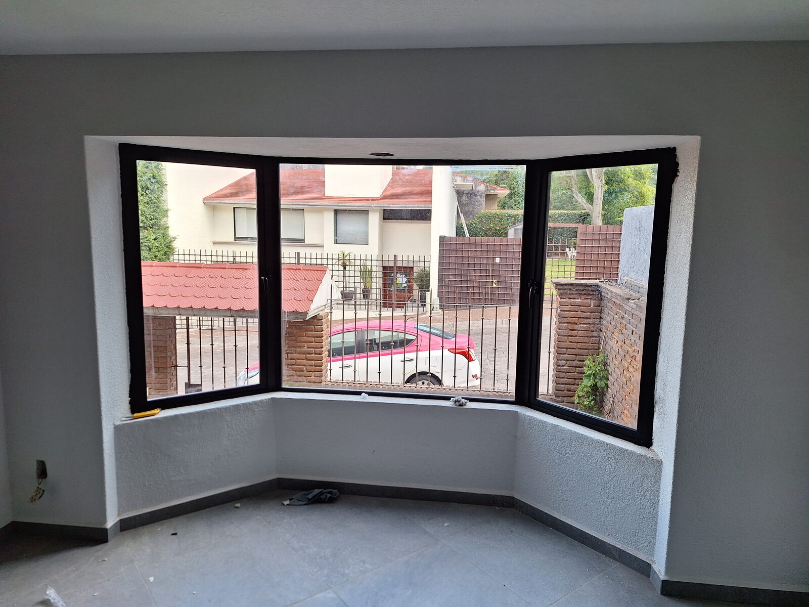 Ventana esquinera de aluminio negro en muro de ladrillo