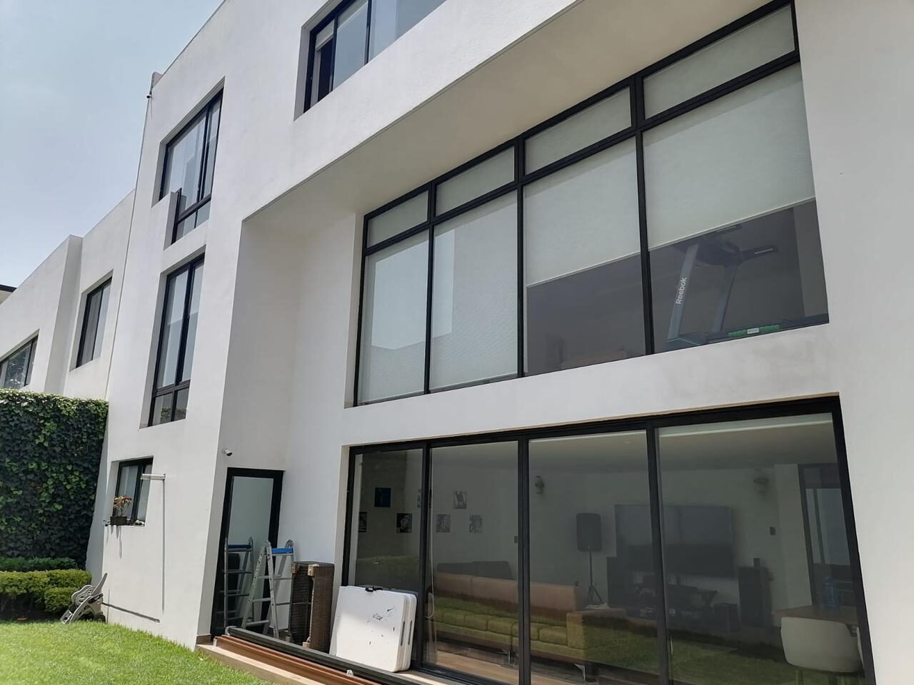 Fachada blanca con ventanales grandes de aluminio negro