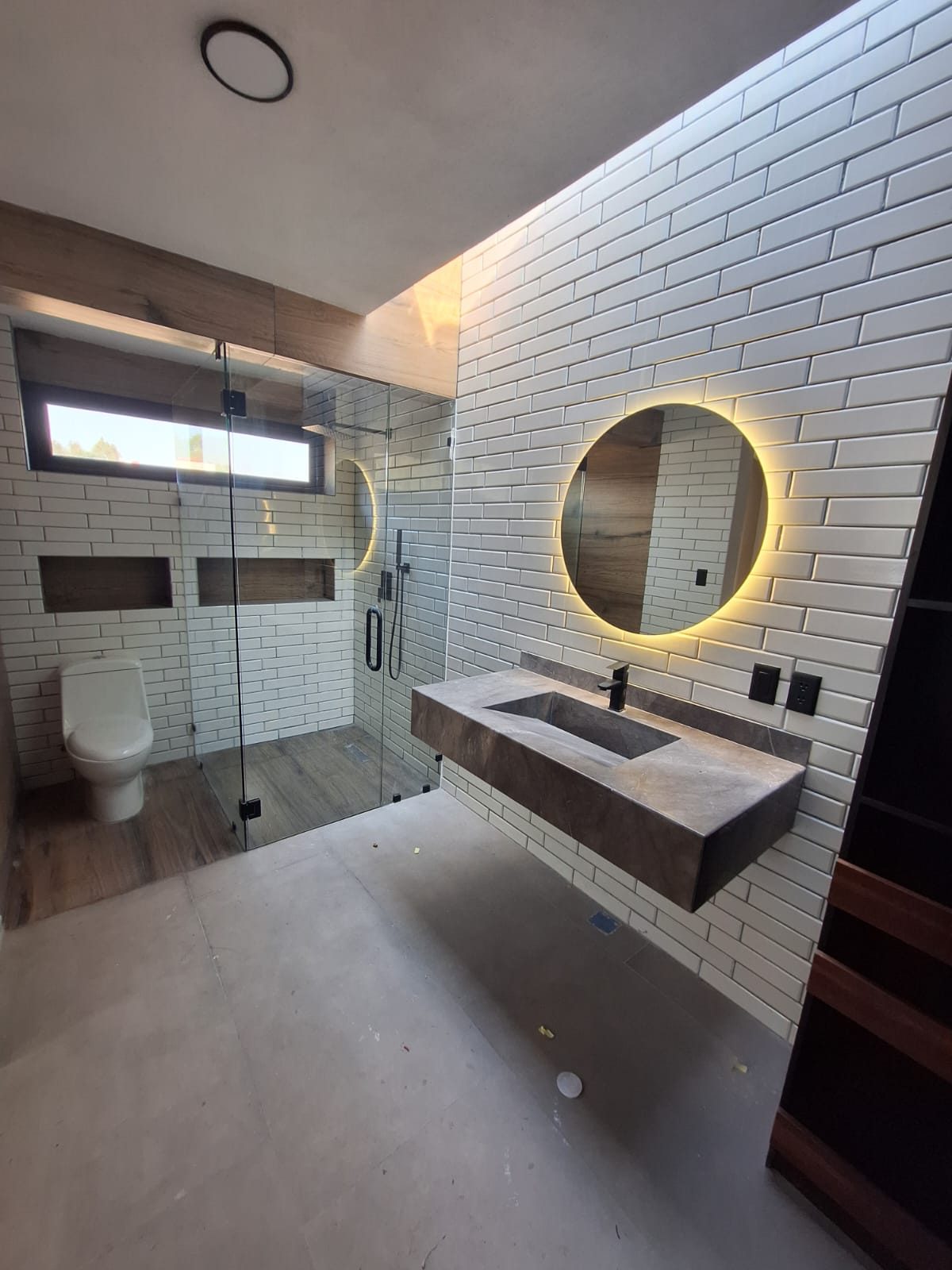Baño con espejo redondo y mosaico blanco